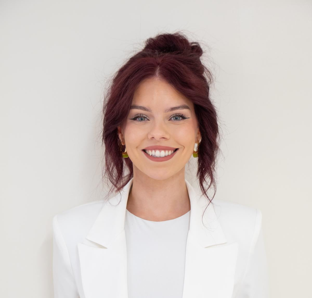 Woman wearing a white blazer over a white shirt with a plain background