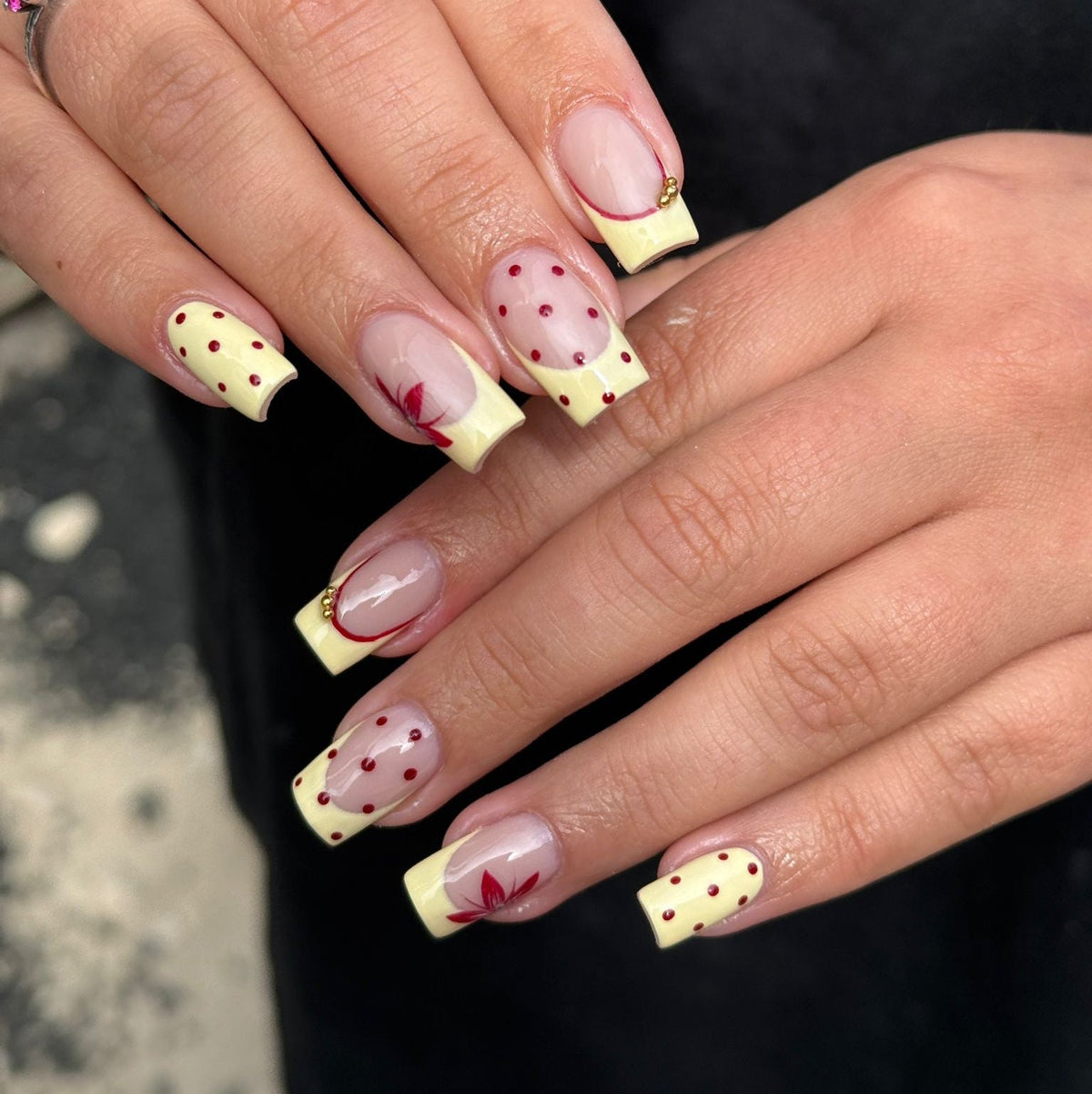 Close-up of a hand with decorative nail art featuring polka dots and red accents.